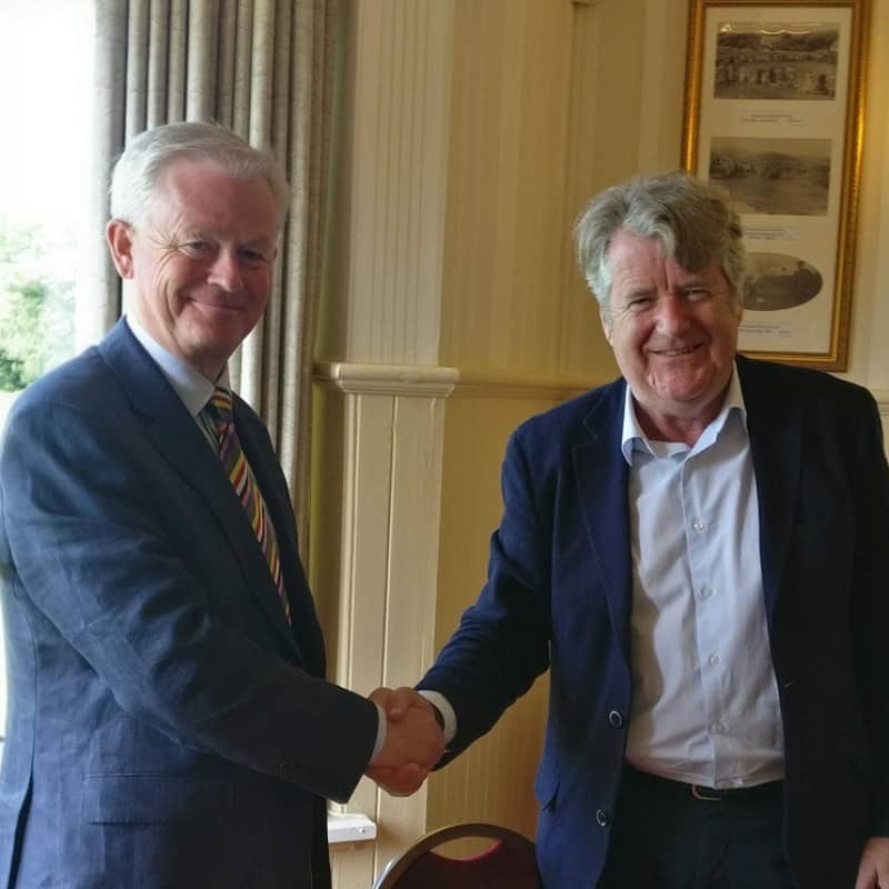 Two men shaking hands in a formal setting.