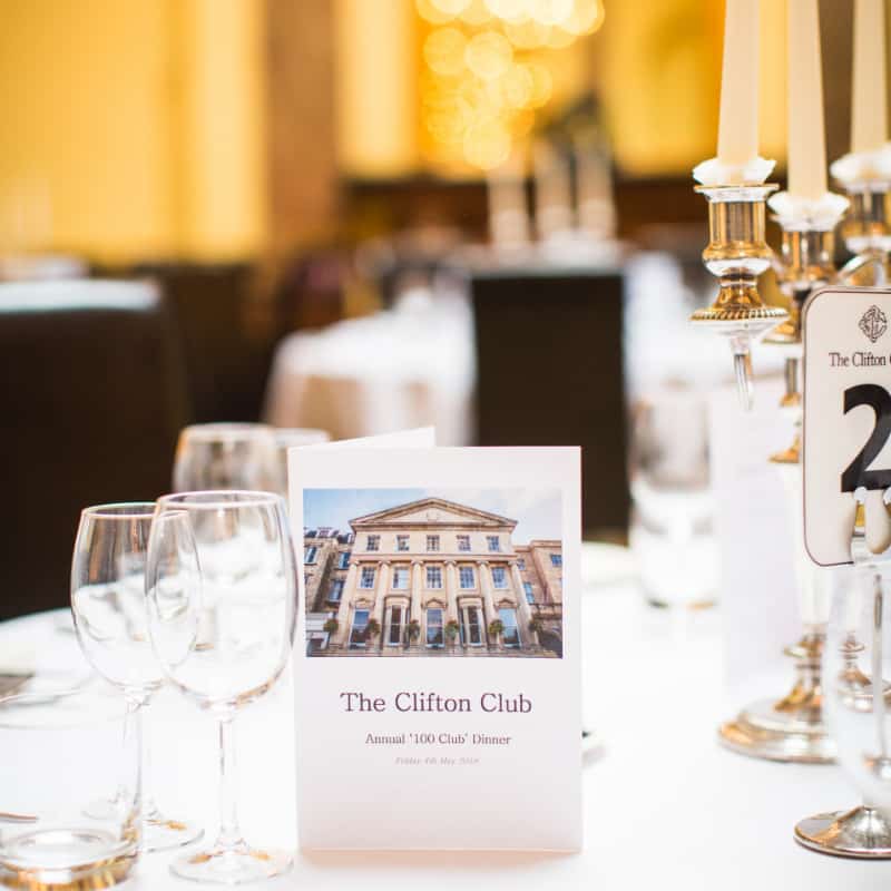 Elegant dining setup for the clifton club annual '100 club' dinner with menu cards on the table.