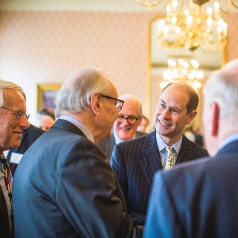 A group of men engaging in a conversation in a room with elegant decor.